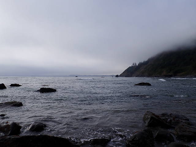 low clouds and ocean mist closing in on moody rocky beach