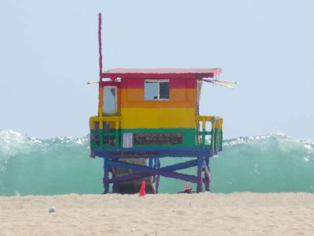 photo of rainbow painted lifeguard station with large wave cresting in the background