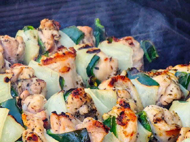 photo of chicken, peppers, and onion skewers on a smoking hot grill