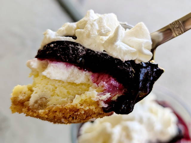 a spoonful of blueberry cheesecake with whip cream