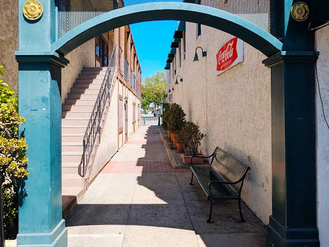 a quaint main street alleyway seen through a turqouise colored metal gate