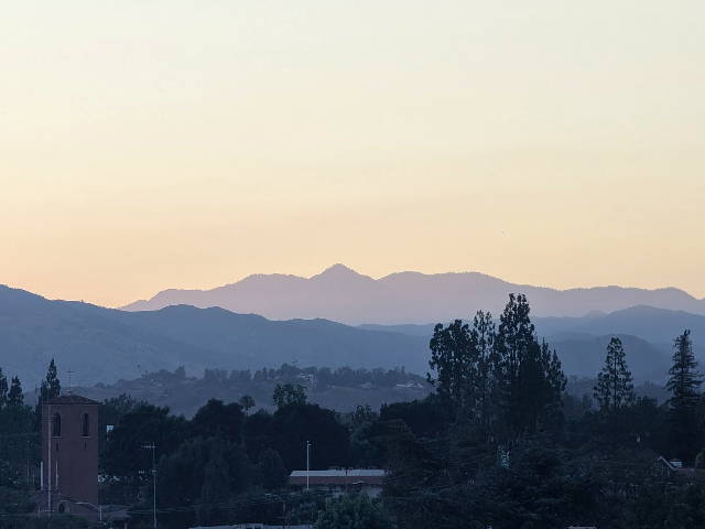 layers of purple mountain haze with trees and buildings below