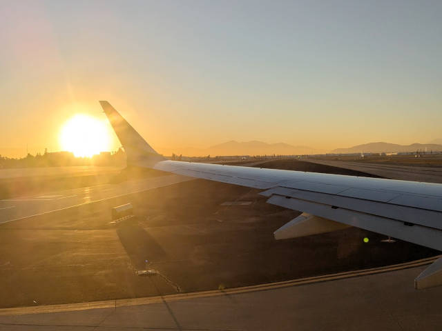 sunrising behind the wing of a plane