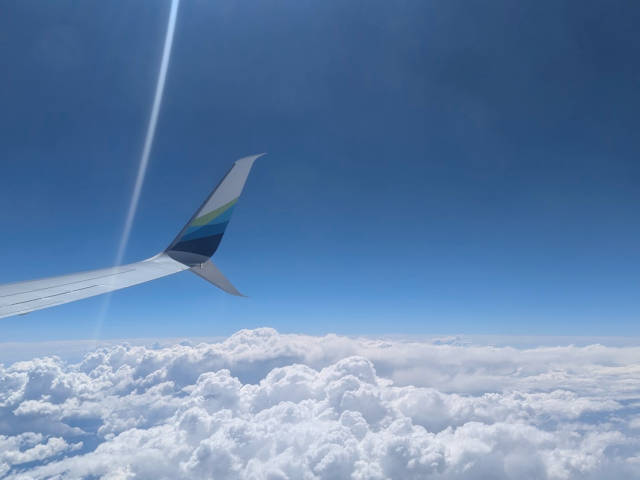 puffy cloud horizon and jet plane wing tip
