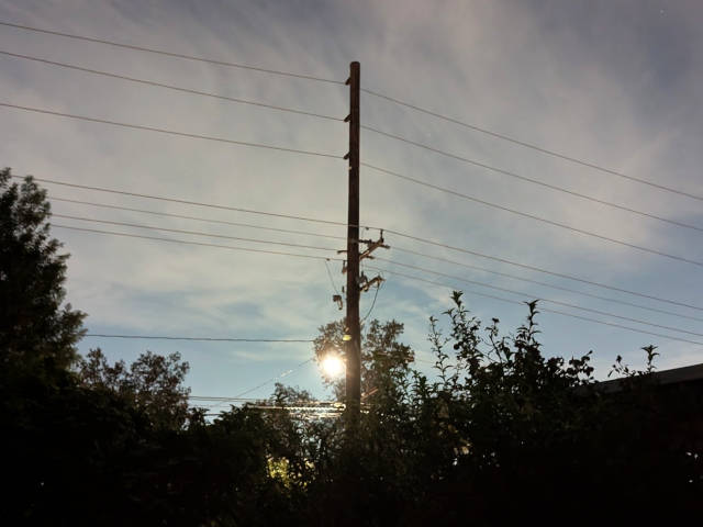 telephone pole with light against moody dark skies