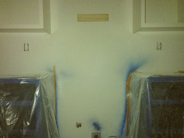 kitchen cabinetry, painted and covered in protective plastic, forming a cross shape against the wall