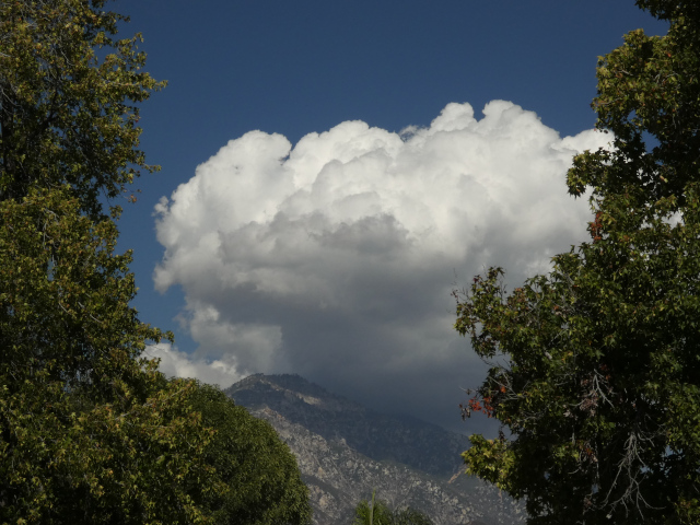 large billowing white cloud casting shadow over nearby mountain