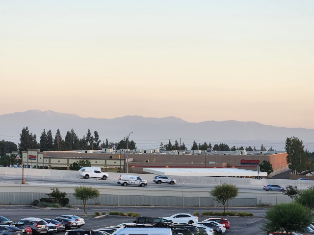wide angle shot of urban sprawl, costco, the distant mountains turning pink in the sunset haze