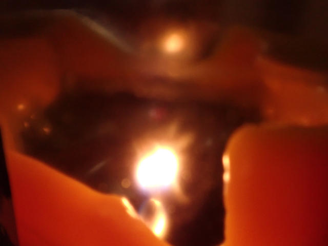 blurred close up on a dim candle in the darkness