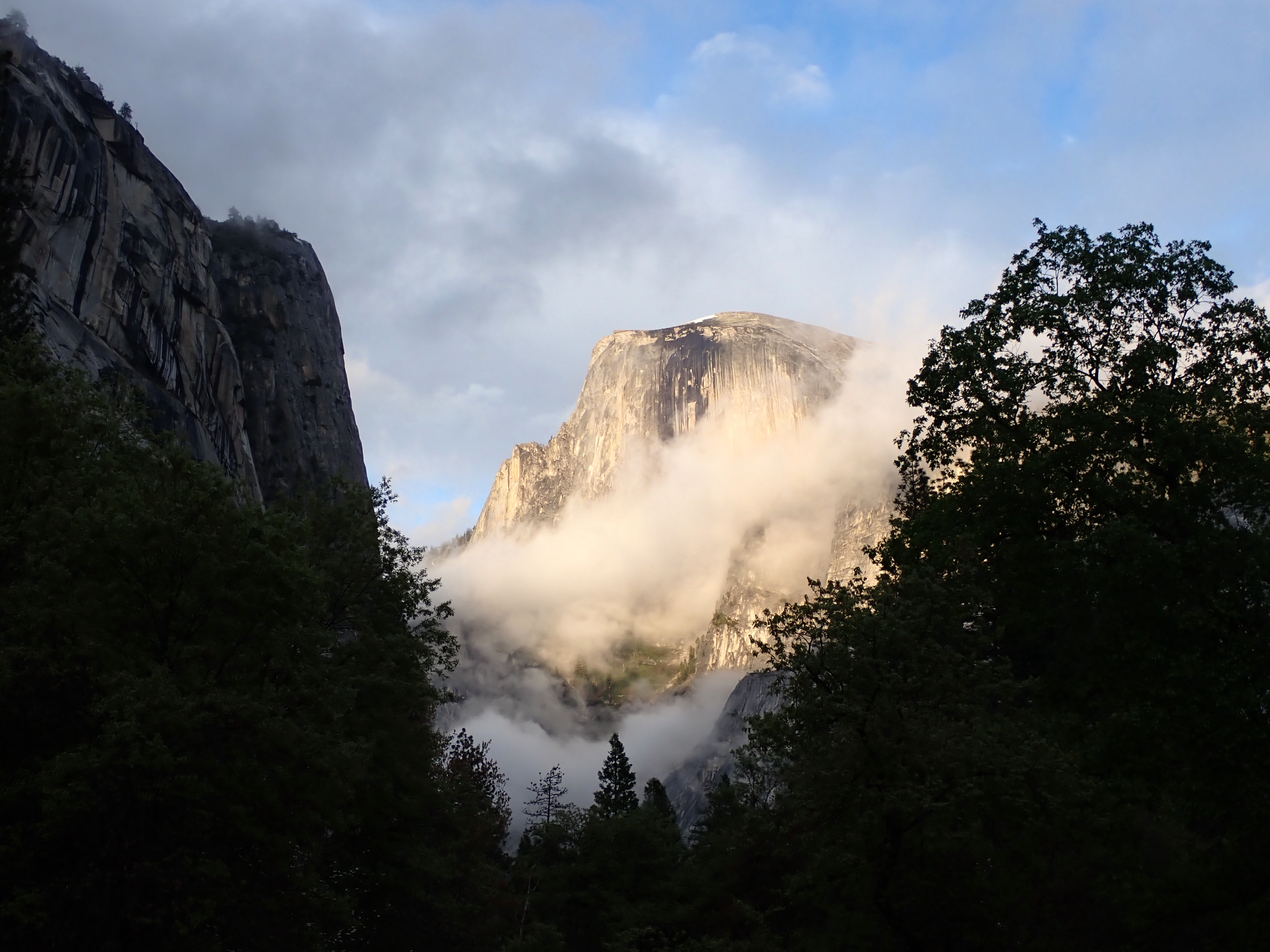 Yomesmite's famed Half Dome with low clouds and highlighted by the setting sun