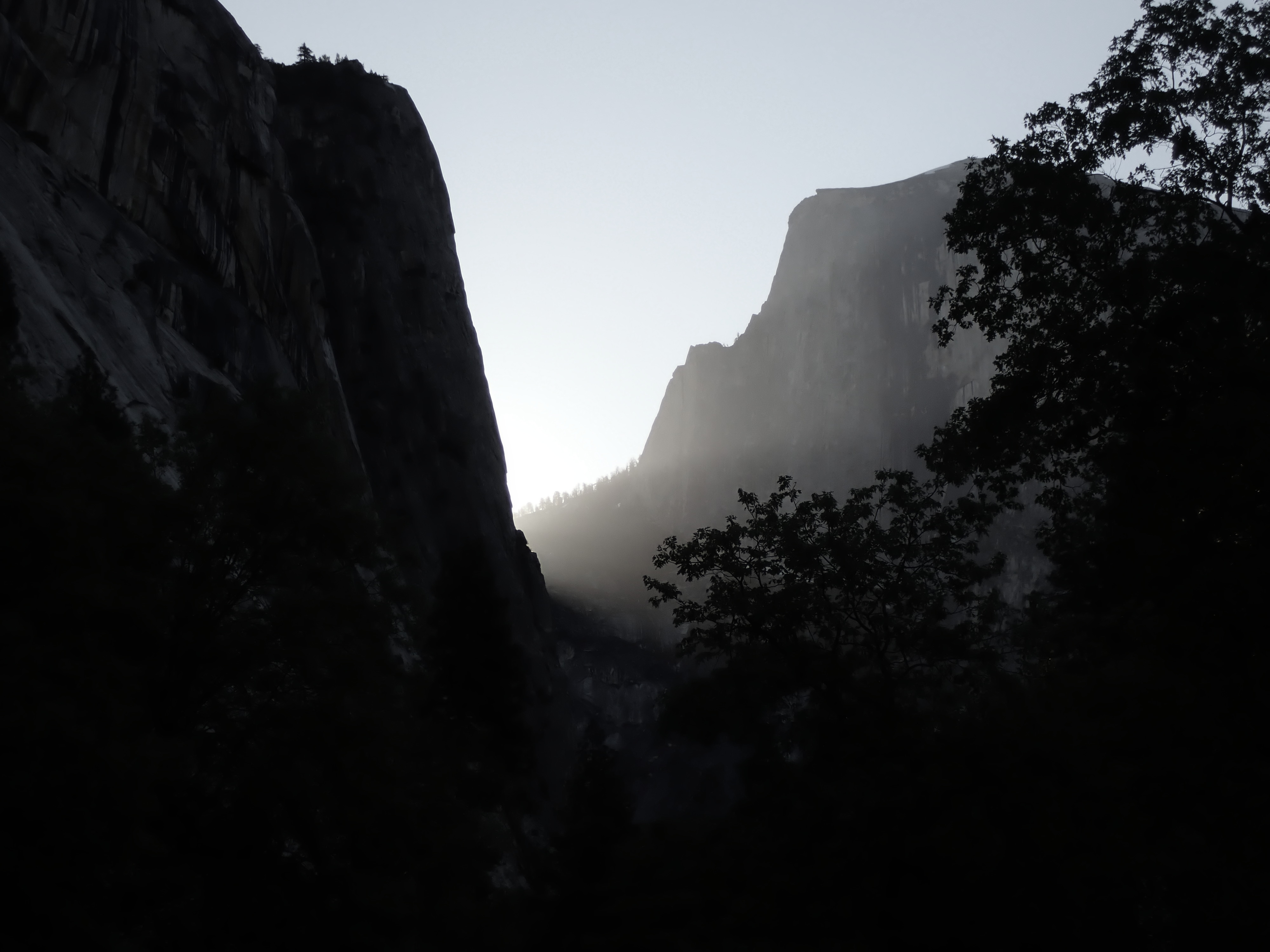 Rays of morning light shine through mist around the base of Yosemite's Half Dome.